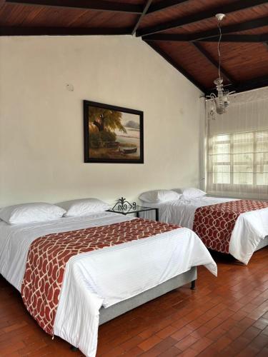 a bedroom with two beds and a painting on the wall at Casa Yolanda Popayán in Popayan