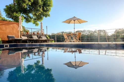 a pool with an umbrella and chairs and a table at EvaZion in Grande Rivière Sud Est