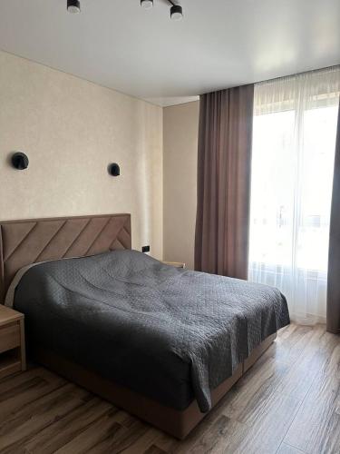 a bedroom with a bed and a large window at Pysanka apartments in Kolomyya