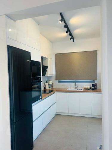 a kitchen with white cabinets and a black refrigerator at Gerani Deluxe Houses 2 in Astypalaia Town