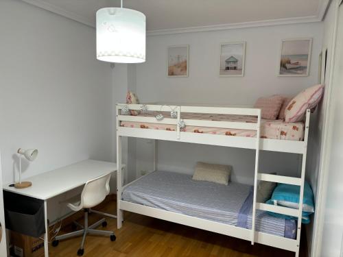 a room with two bunk beds and a desk at El pisuco in Miengo