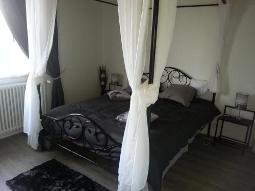a bedroom with a bed with curtains on it at Le Tacot in Auxon-Dessus