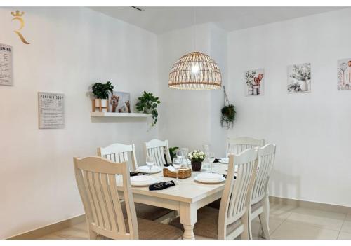 a white dining room table with white chairs and a chandelier at Al Reem 2BR - Stylish Family Retreat in Abu Dhabi