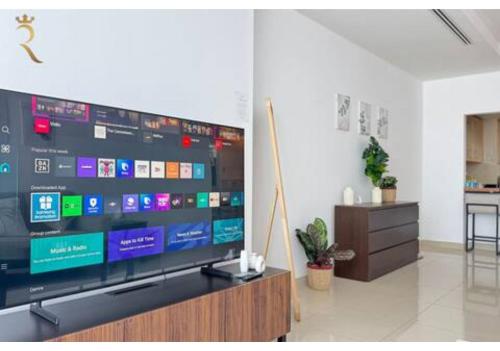 a flat screen tv sitting on a stand in a living room at Al Reem 2BR - Stylish Family Retreat in Abu Dhabi