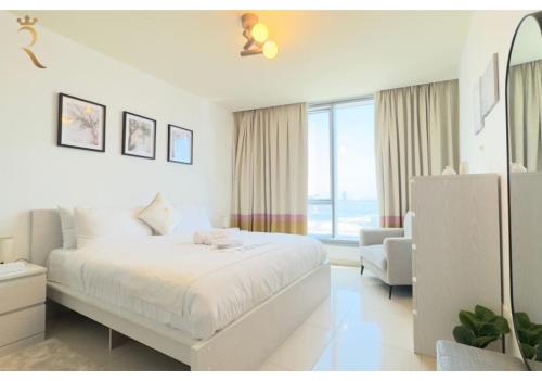 a white bedroom with a bed and a chair at Al Reem 2BR - Stylish Family Retreat in Abu Dhabi