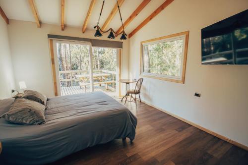 a bedroom with a bed and a table and window at Aldea Molco El Pellin in Villarrica