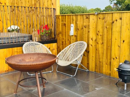 a patio with two chairs and a table and a fence at The Shepherds Chalet in Garstang