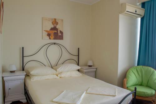 a bedroom with a bed and a green chair at ElStefanino House in Eforie Nord