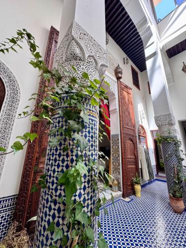 a hallway with blue and white tiles and plants at Palais Nazha Fes - Luxury Lodging in Fès