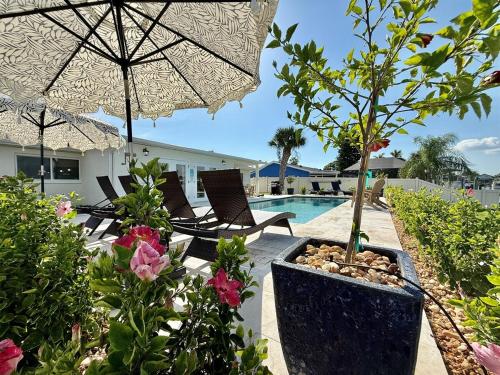 a patio with a pool and an umbrella and flowers at Brand New Pool! Waterfront Canal Luxury Home in Apollo Beach