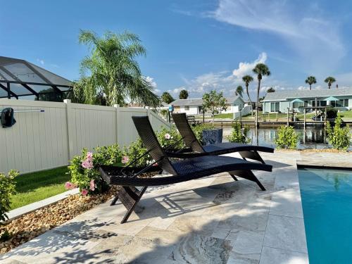 two chairs sitting on a patio next to a swimming pool at Brand New Pool! Waterfront Canal Luxury Home in Apollo Beach