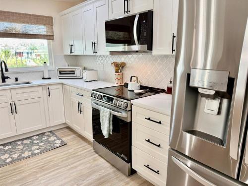 a kitchen with white cabinets and a stainless steel refrigerator at Brand New Pool! Waterfront Canal Luxury Home in Apollo Beach