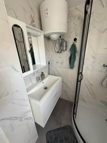 a white bathroom with a sink and a shower at Počitniška hiša ˇGORICEˇ in Moravske Toplice