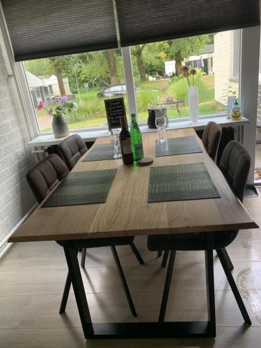 a wooden table with chairs and a large window at Vakantiehuis ontdek Zuid - Limburg in Simpelveld