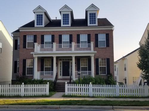 a red brick house with a white fence at Gigi's luxurious Arora Hills 2 BdRm, 2 Baths Apt in Clarksburg