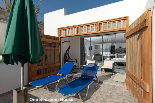 a patio with two blue chairs and an umbrella at Deja Dream Homes in Schinopi