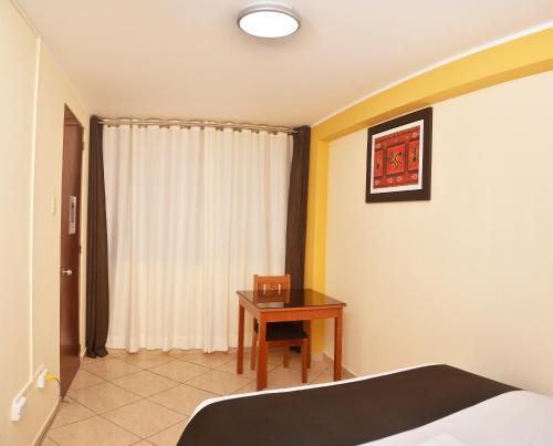 a bedroom with a desk and a bed and a table at Hostel Esperanza in Lima