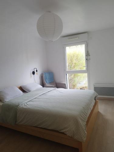 カーンにあるLe Cosy avec jardin terrasse couverte et parking gratuitの大きなベッドと窓のある寝室