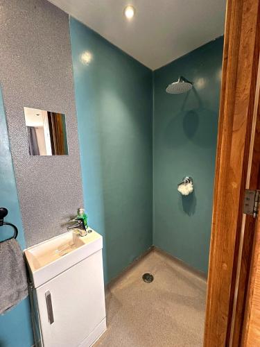 a bathroom with blue walls and a sink and a mirror at Seaside Apartment, on the doorstep of the Beach! in Margate
