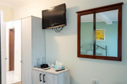 a bathroom with a mirror and a tv on the wall at ElStefanino House in Eforie Nord