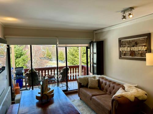 a living room with a couch and a balcony at Departamentos Exclusivos Termas de Chillán in Nevados de Chillan