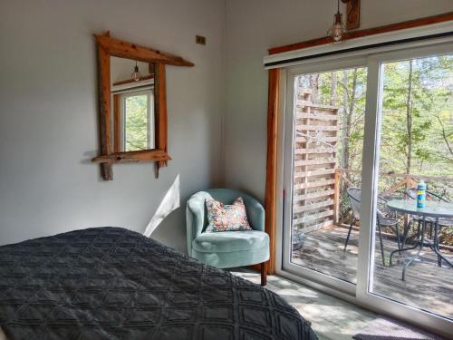 a bedroom with a bed and a chair and a patio at Cabañita con Tinaja Ruta657 in Coihaique
