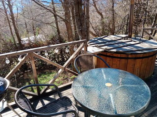 a table and chairs on a deck with a barrel at Cabañita con Tinaja Ruta657 in Coihaique