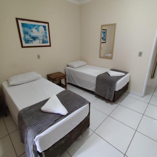 a hotel room with two beds and a mirror at Hotel Fênix in Florianópolis