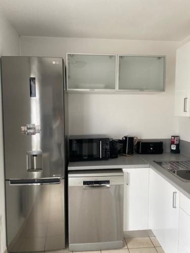 a kitchen with a stainless steel refrigerator and white cabinets at Appartement 7 pers à Disneyland Paris in Chessy