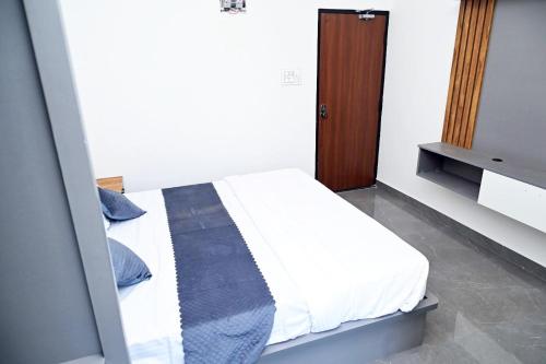a bedroom with a white bed and a wooden door at The REEF LOUNGE in Mandya