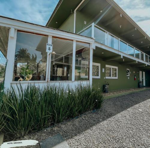 a green building with large windows and plants at Hotel Girassol in Imbé
