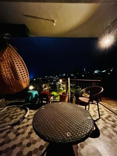 a table and chairs on a balcony at night at The Hp 39 House in Dharmsala