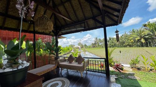 a porch with a chair and a view of a field at Eco Oasis Wooden Villa Ubud in Tegalalang
