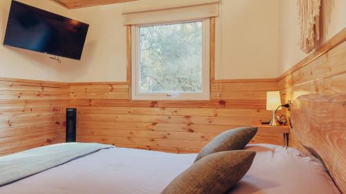 a bedroom with a bed with a tv on the wall at Aldea Molco Avellano in Villarrica