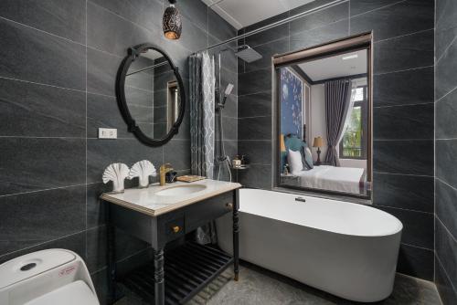 a bathroom with a tub and a sink and a mirror at Indochine Boutique Hotel Ninh Bình in Ninh Binh