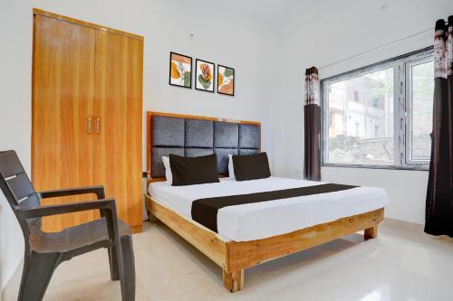 a bedroom with a bed and a chair in it at Hotel O Kashika Inn in Kichha