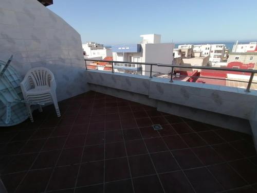 a balcony with a chair and a view of the city at دوبليكس ميرامار مرتيل in Martil