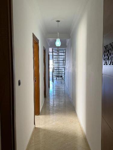 a hallway with white walls and a hallway with a stairway at دوبليكس ميرامار مرتيل in Martil