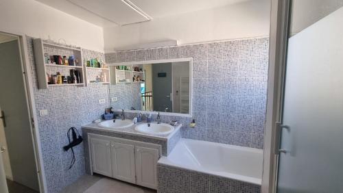 une salle de bain avec deux lavabos, une baignoire et un miroir dans l'établissement Charmante maison en Provence, à La Crau