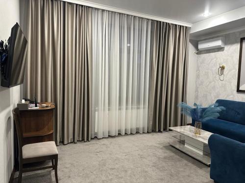 a living room with a blue couch and curtains at Grand Way Hotel in Taraz