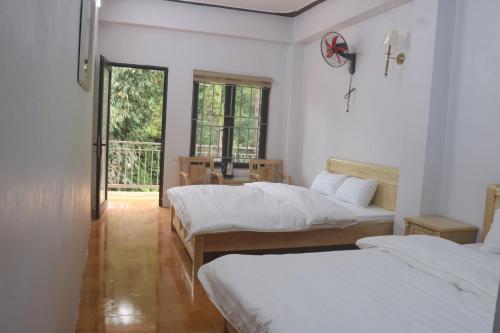 a bedroom with two beds and a desk and a window at Nhà Bên Suối 