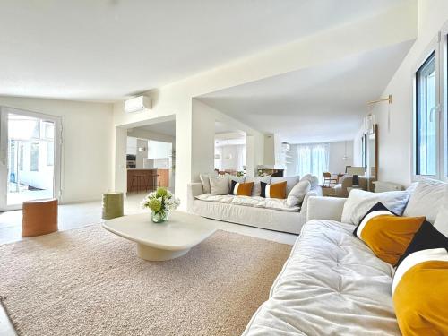 a living room with two couches and a table at Villa luxueuse avec piscine chauffée in Gujan-Mestras