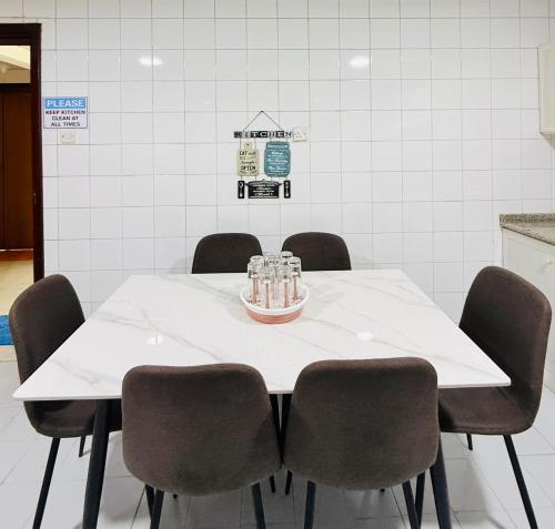 a white table with four chairs around it at Aplyns Dormitory Male&Female,Sharjah in Jazīrat al Ḩibāb