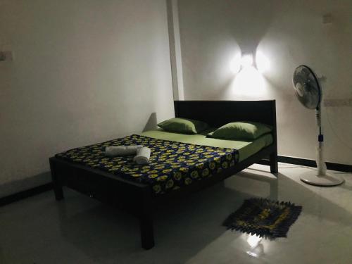 a bedroom with a bed with a lamp and a fan at Ops Poinix Hotel in Weerawila