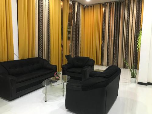 a living room with two black chairs and a table at Ops Poinix Hotel in Weerawila
