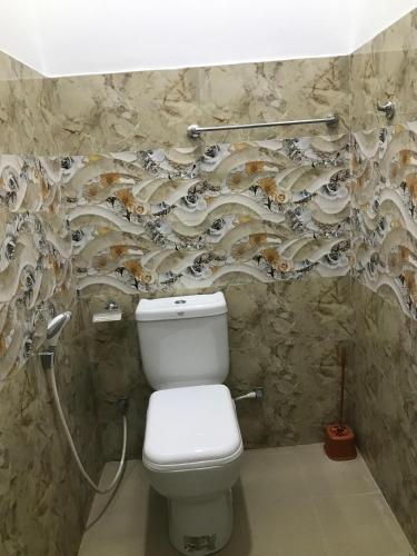 a bathroom with a toilet and a stone wall at Ops Poinix Hotel in Weerawila