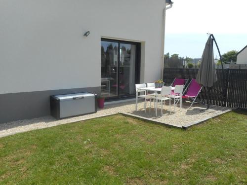 a patio with a table and chairs and an umbrella at Le Ptit Zef in Pluduno