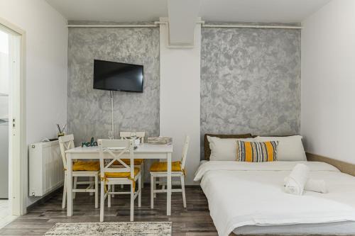 a bedroom with two beds and a table and a tv at JAD - Comfortable -3 Rooms & 2 Rooms Apartments in Braşov