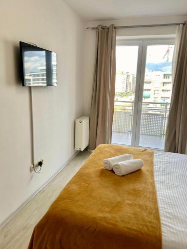 a bedroom with a bed with a tv and a window at JAD - Comfortable -3 Rooms & 2 Rooms Apartments in Braşov