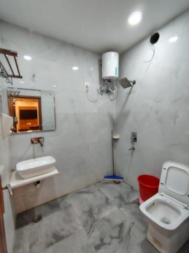 a bathroom with a sink and a toilet and a mirror at Hotel pinaka in Vrindāvan